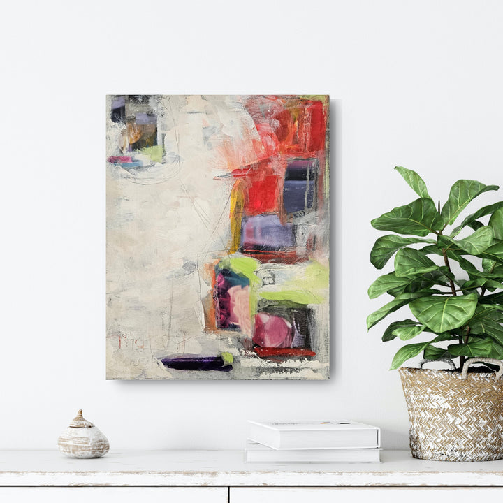 Abstract art piece with colorful geometric shapes on a textured background on white wall above a shelf