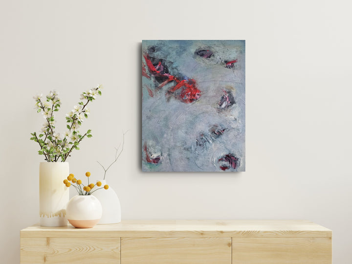 Abstract grey and red painting for sale shown on a wall above a wooden console table with decorative items.