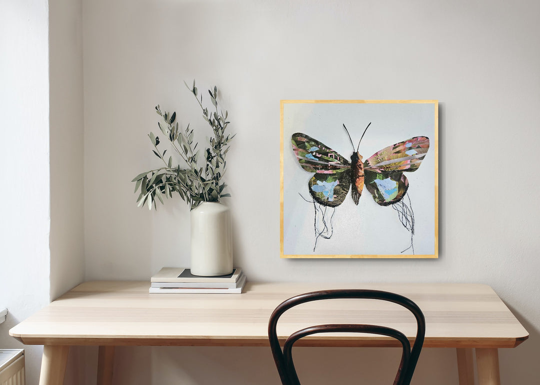 Sprite is a butterfly / moth collage created with recycled magazine bits embellished with delicate hand stitching. Museum-quality wall art. Displayed here over a desk.